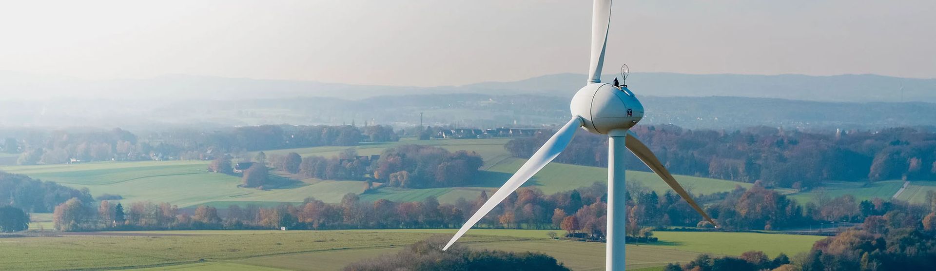 A wind turbine stands tall in a lush green field, symbolizing renewable energy and environmental sustainability.