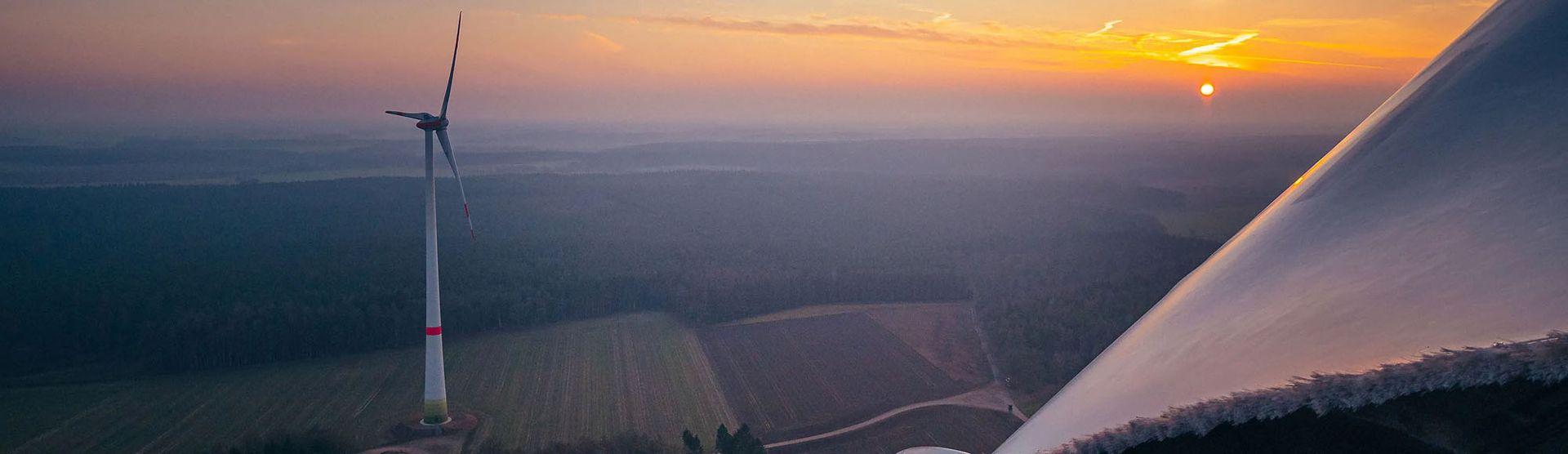 A wind turbine silhouetted against a vibrant sunset sky, showcasing renewable energy in harmony with nature.